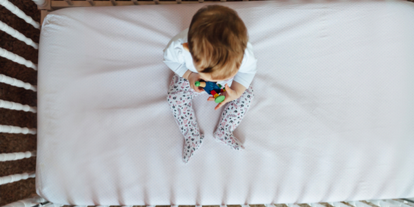 a baby in a crib photographed from above